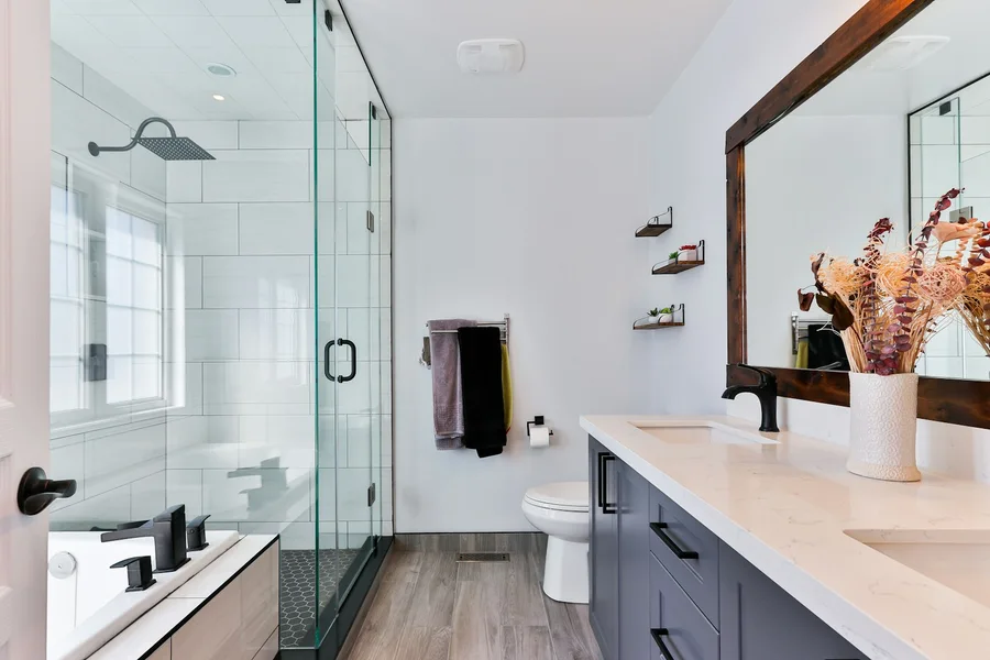 Bathroom with a dark vanity, pale surfaces and glass shower screen